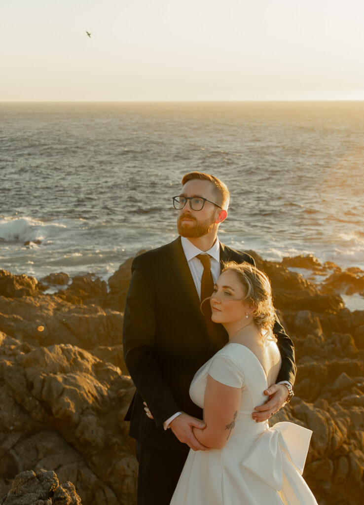 Bride and groom embracing on coastal cliffs at Garrapata State Park in Big Sur