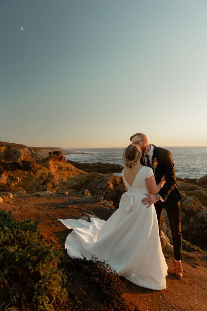 Bride and groom kissing on coastal cliffs at Garrapata State Park in Big Sur