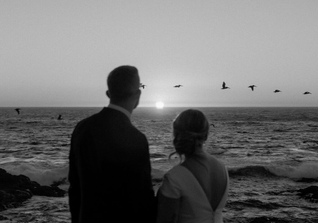 Couple watching sunset over ocean at Garrapata State Park in Big Sur