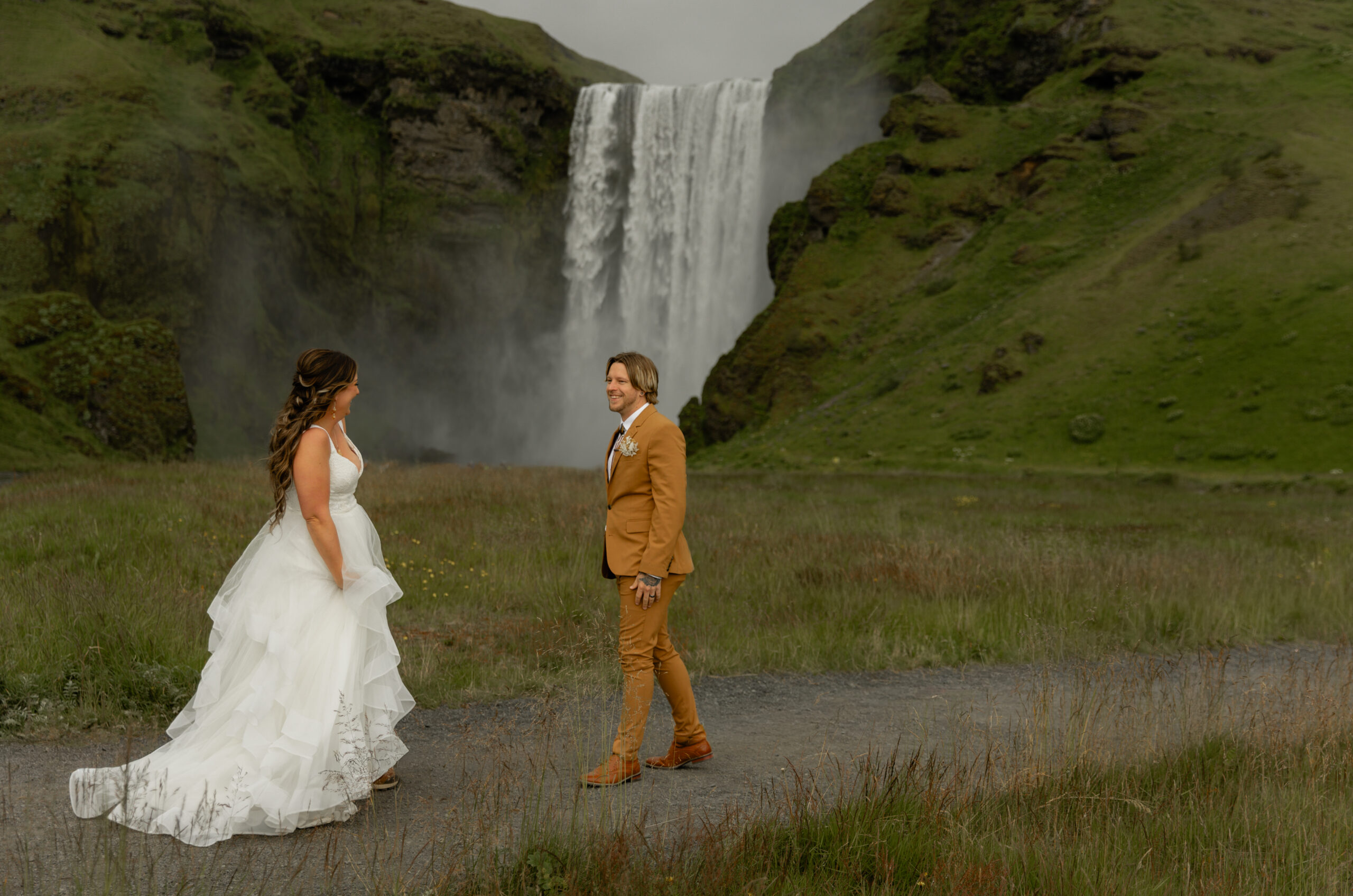 Bride and groom standing together in front of Skógafoss waterfall during Iceland vow renewal