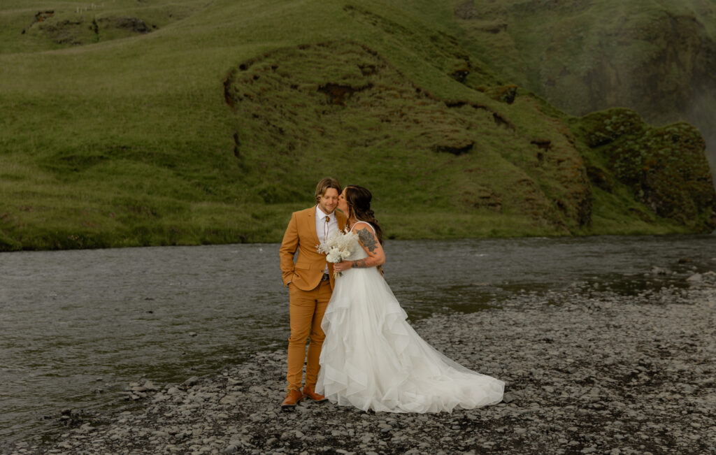 bride and groom kissing in front of Skógafoss waterfall during Iceland vow renewal