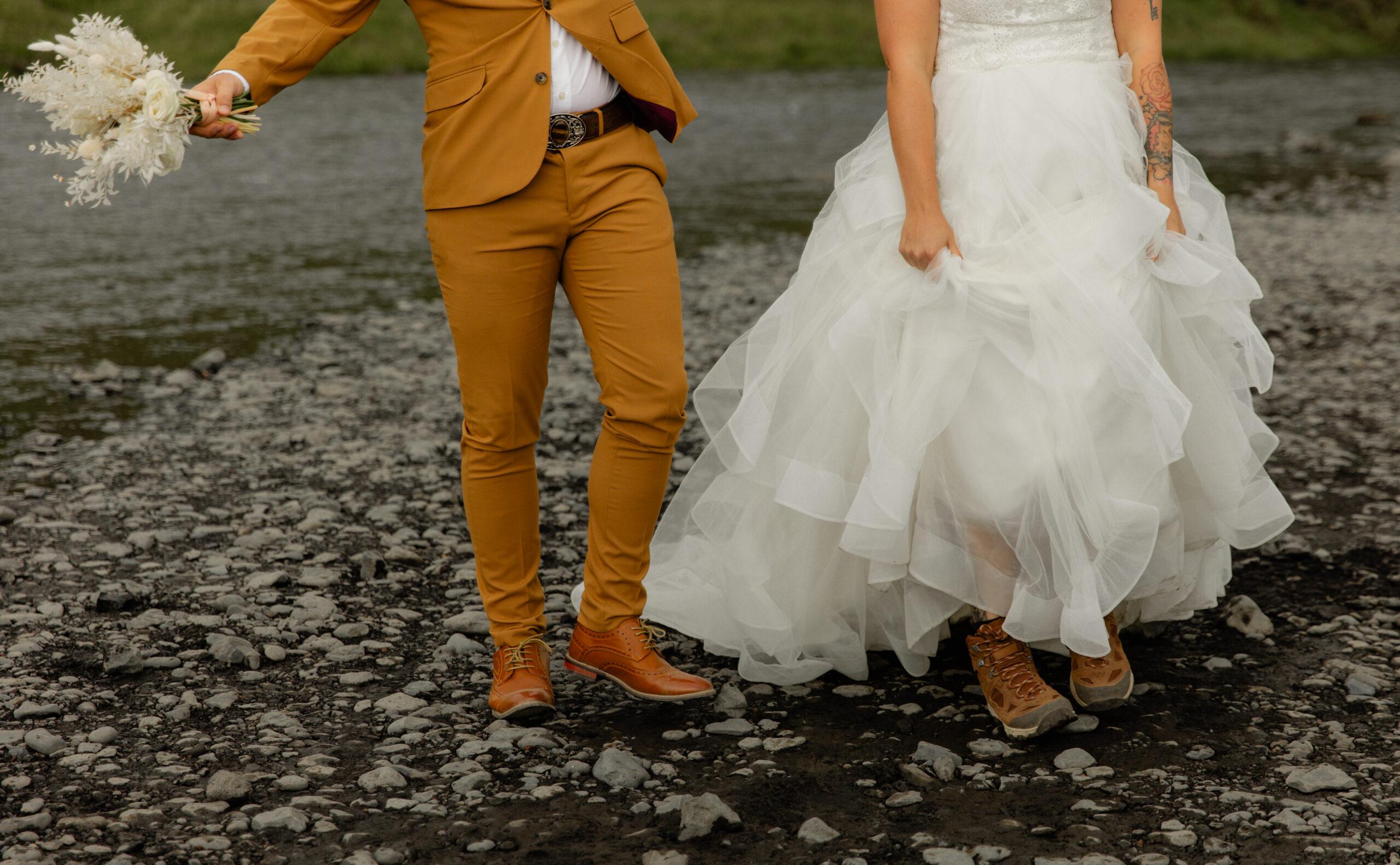 Close-up photo of bride and groom walking across black volcanic rocks during Iceland vow renewal