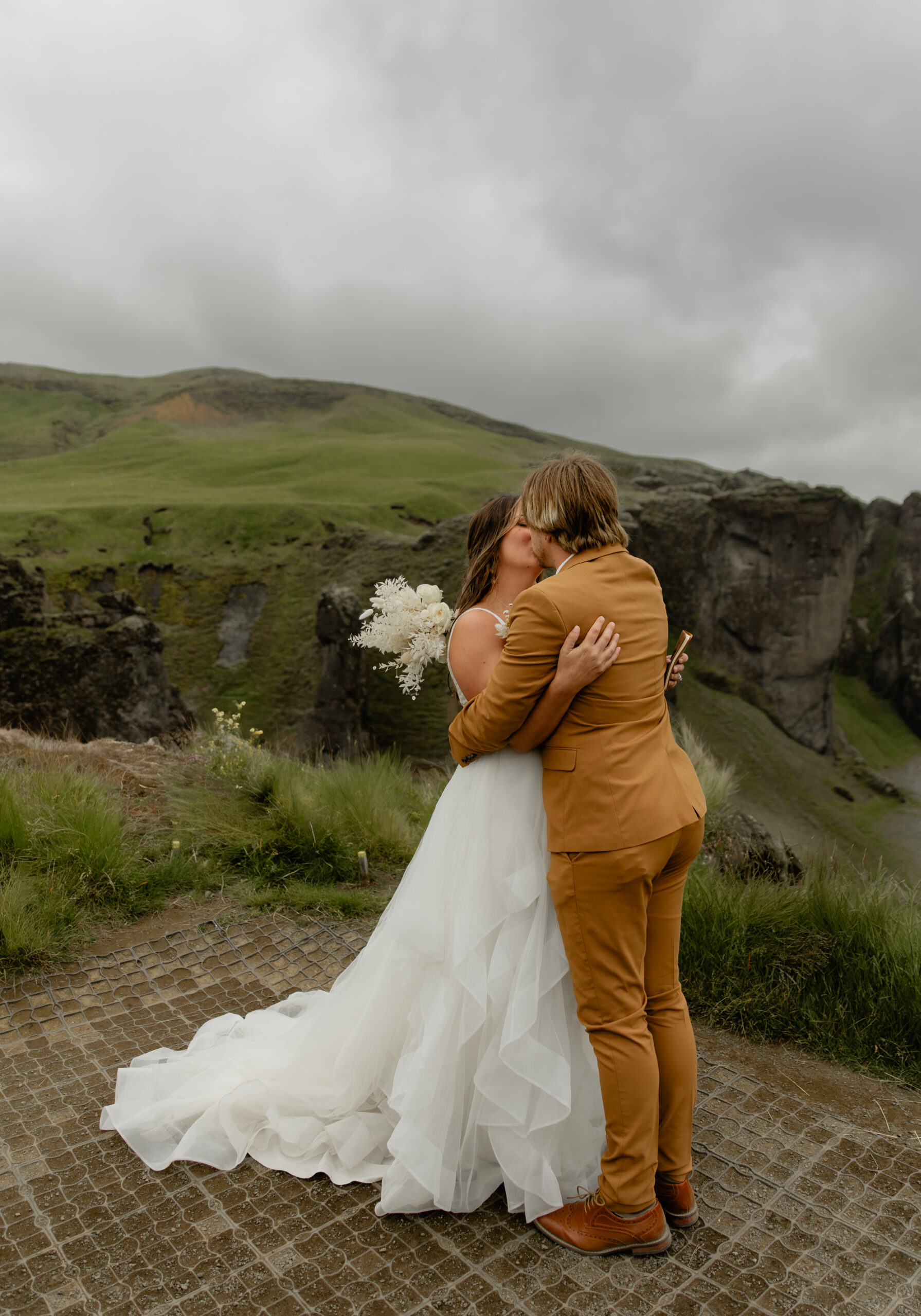 Bride and groom embracing at Fjaðrárgljúfur Canyon during their Iceland vow renewal