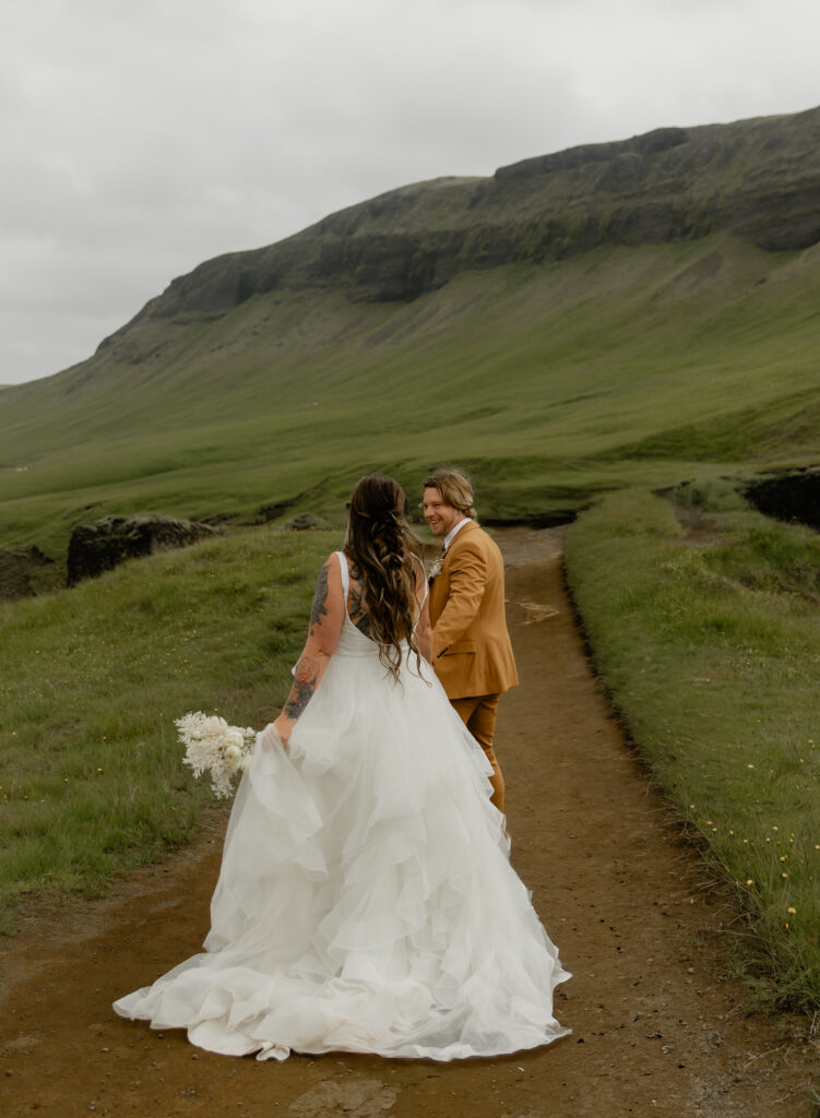 Bride and groom walking along canyon path at Fjaðrárgljúfur during Iceland vow renewal