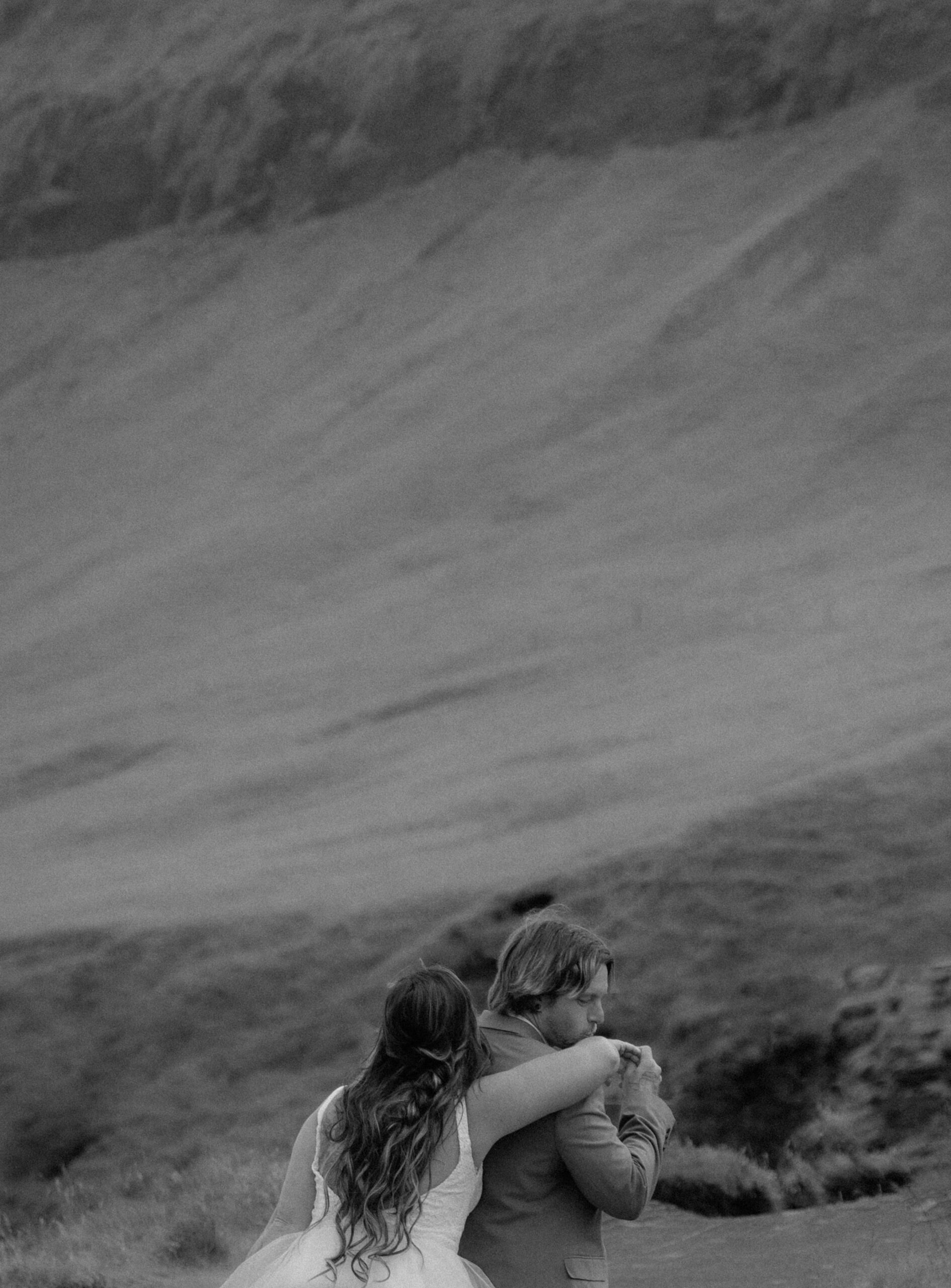 Black and white documentary-style portrait of couple embracing in Iceland landscape