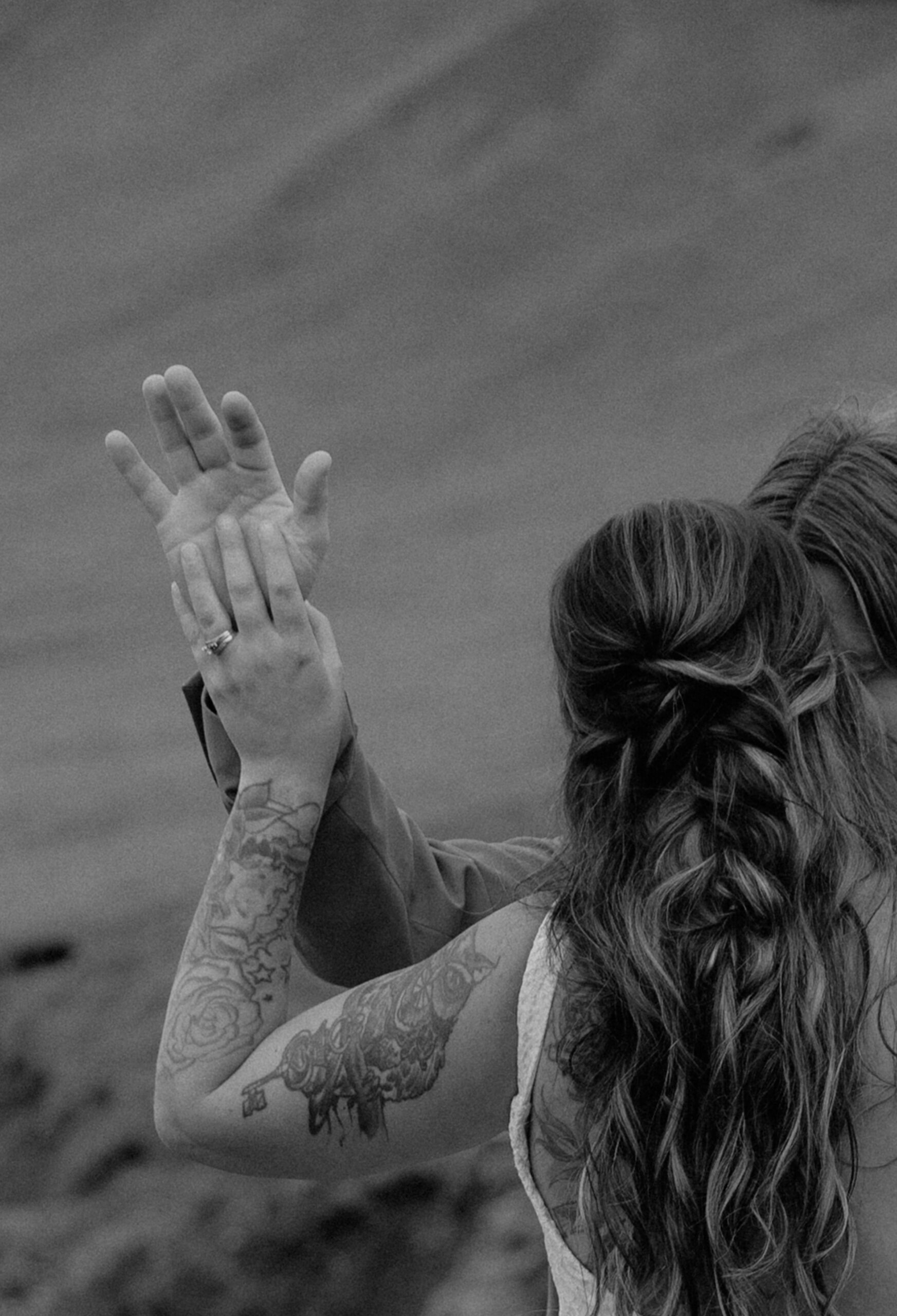 Black and white detail photo of bride raising hand during emotional vow renewal in Iceland