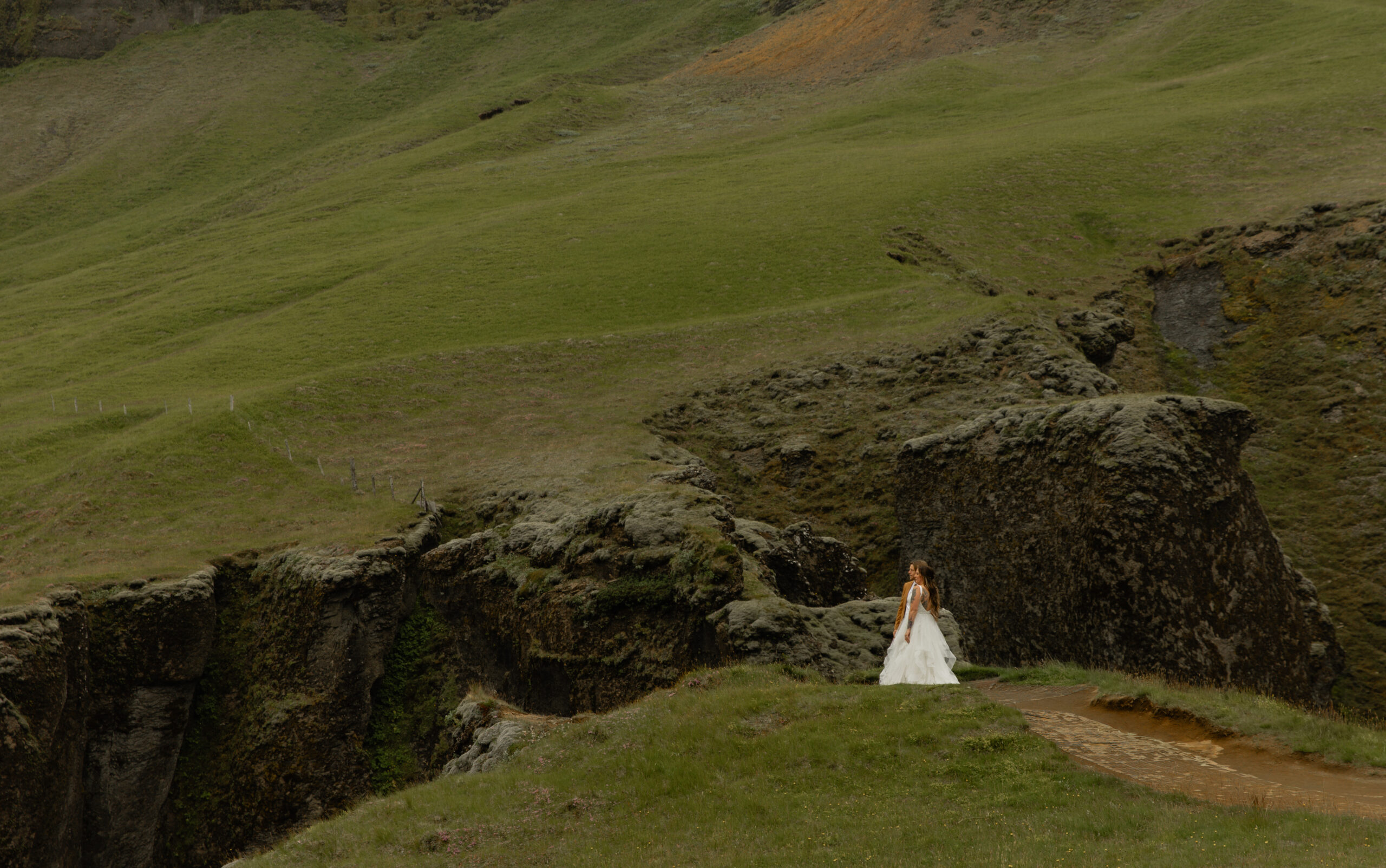 Wide landscape portrait of bride standing at Fjaðrárgljúfur Canyon during Iceland vow renewal