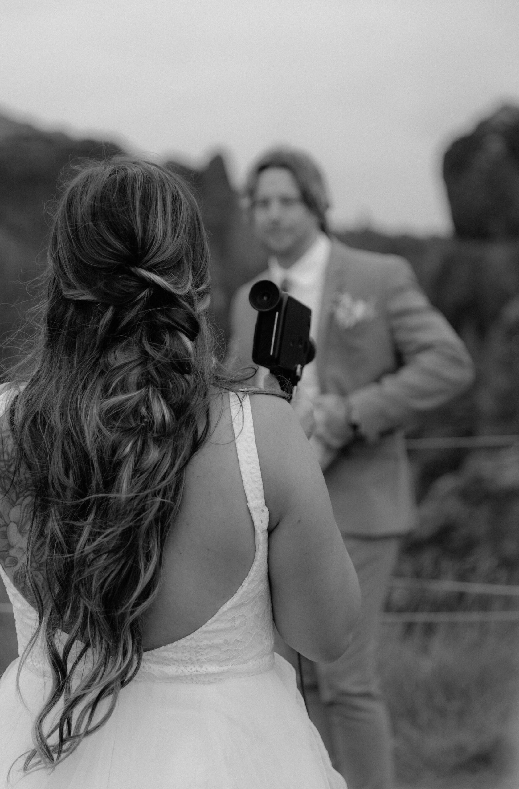 Black and white photo of bride filming groom during private vow ceremony in Iceland
