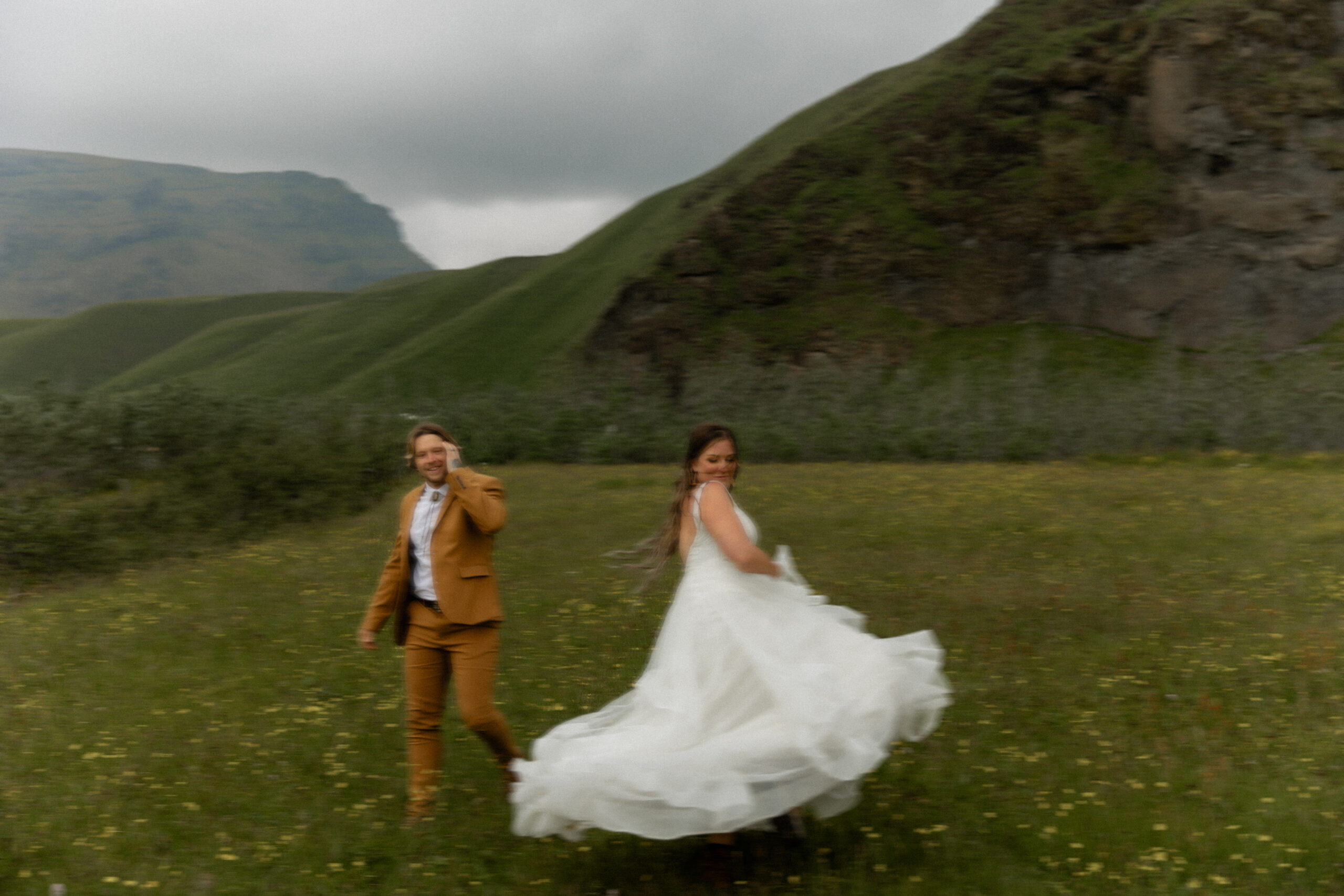 Bride and groom running through wildflower field during adventurous Iceland vow renewal portraits