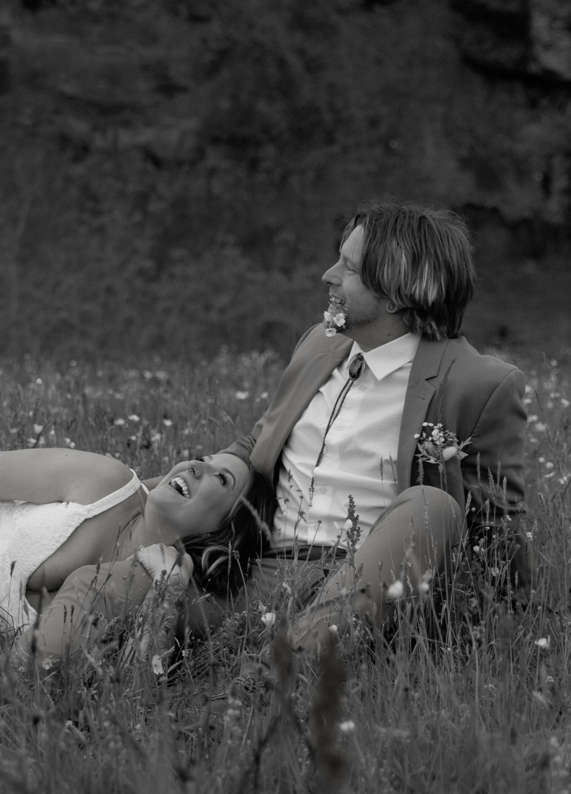 Black and white portrait of couple laughing together in Iceland wildflower field