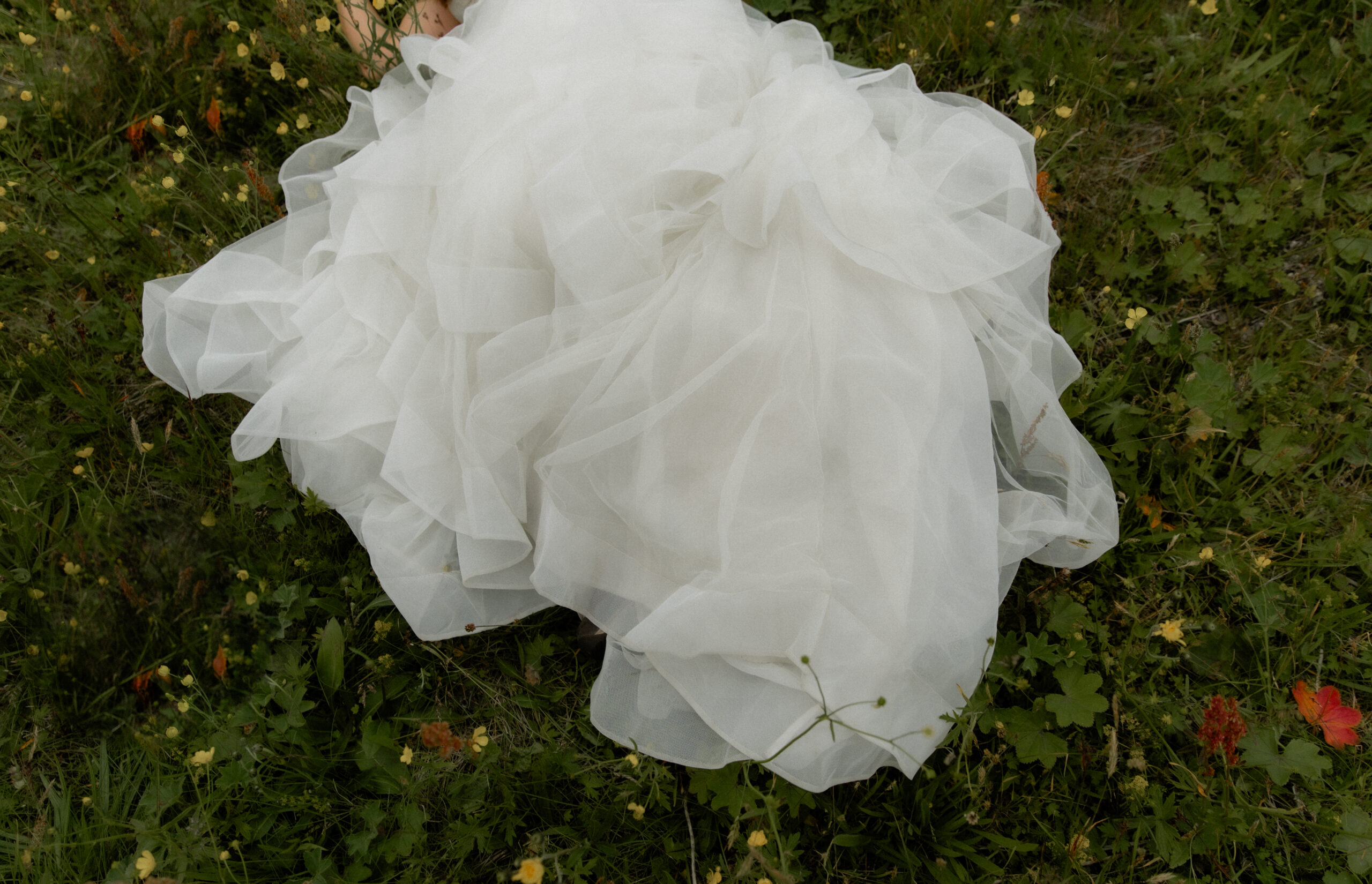 Close-up detail photo of layered wedding dress in Iceland wildflowers