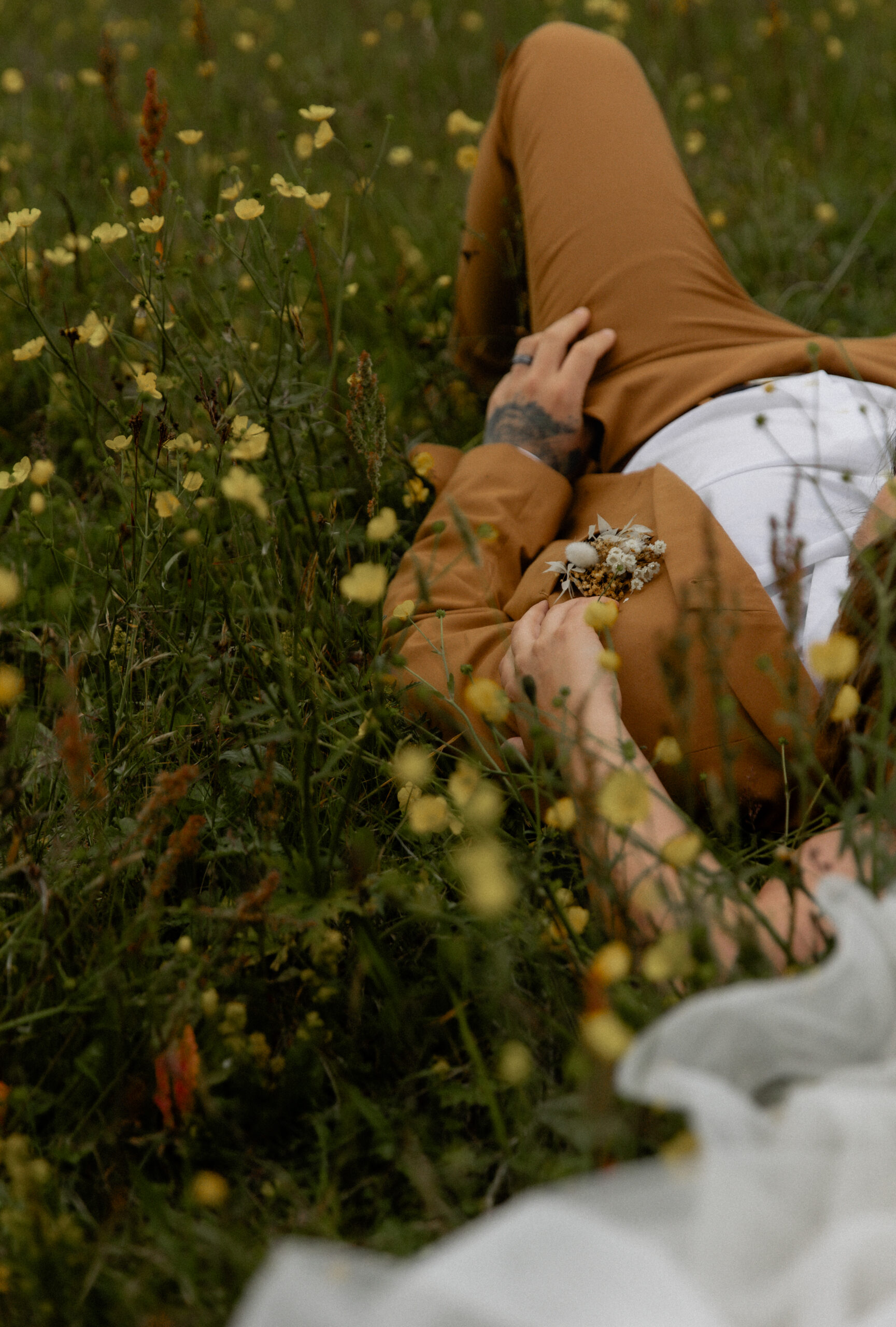 Close-up detail photo of groom lying in Iceland wildflowers during elopement portraits